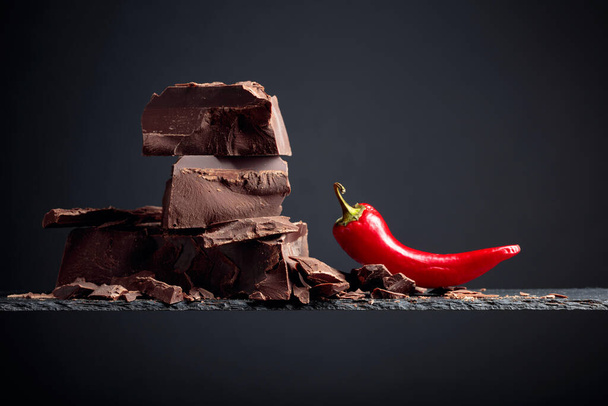 Zwarte chocolade met rode peper op een donkere achtergrond.  - Foto, afbeelding