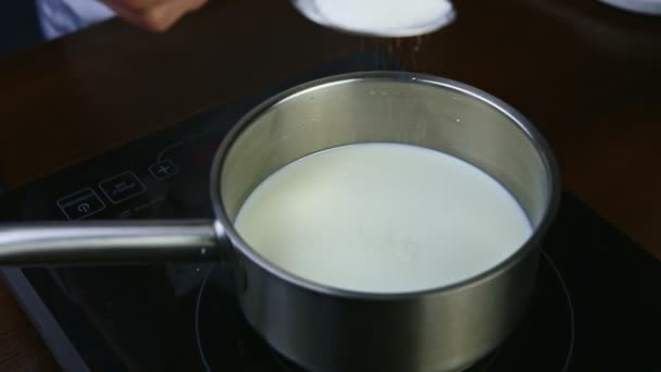 замедленное движение женской руки ложкой разбрасывает сахар в горячее молоко в металлической кастрюле
 - Кадры, видео