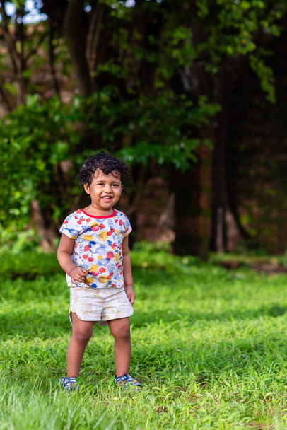 Jolie fille indienne ludique enfant / nourrisson jouant à l'extérieur avec un beau fond environnemental - Photo, image