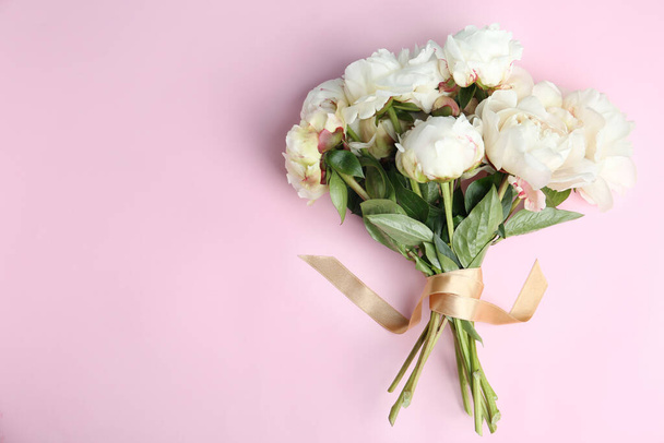 Bouquet of beautiful peonies with ribbon on pink background, flat lay. Space for text - 写真・画像