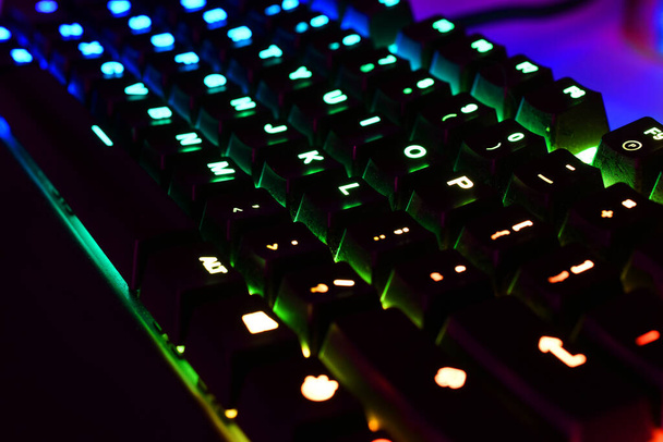 A low angle image of a back lit computer keyboard with red, blue, and green lights. .  - Photo, Image