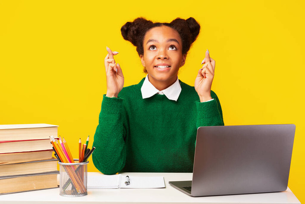 Χαρούμενη μαύρη κοπέλα σταυρώνει τα δάχτυλα χρησιμοποιώντας φορητό υπολογιστή - Φωτογραφία, εικόνα