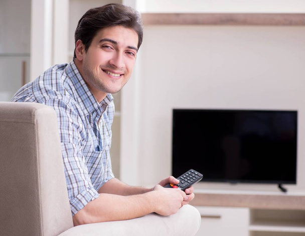 Genç adam evde televizyon izliyor. - Fotoğraf, Görsel