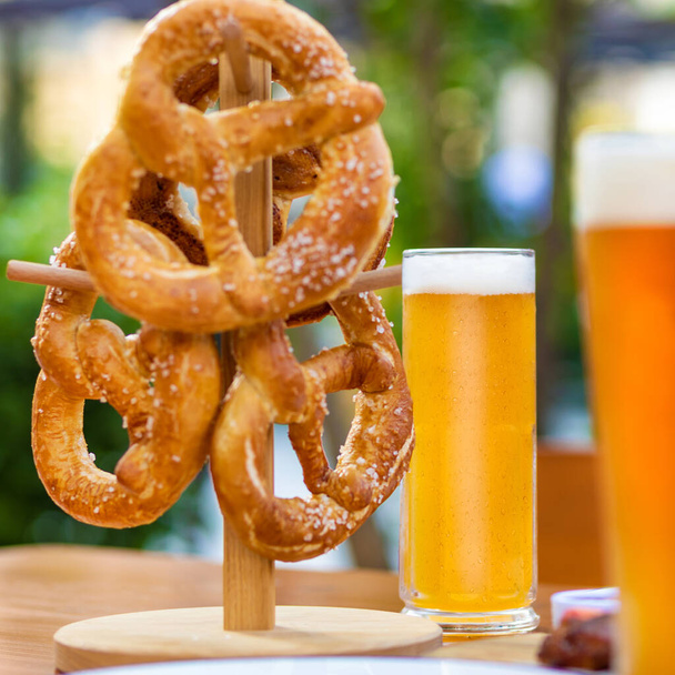 Beer mugs with pretzel on the table, green background - Foto, Imagen