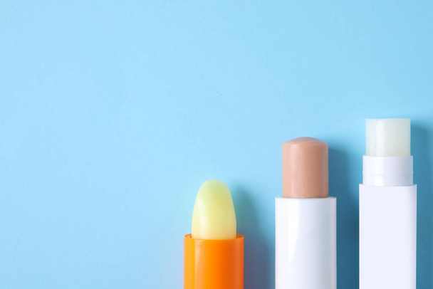 Hygienic lipsticks on light blue background, flat lay. Space for text - Foto, Imagem