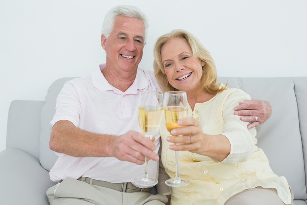 Senior couple toasting champagne flutes at home - Foto, imagen