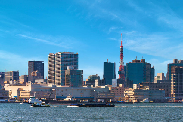 Barcaças rebocadas por rebocadores navegando em frente ao Terminal Shibaura no porto de Tóquio com os arranha-céus do distrito de Shiba e a Torre de Tóquio na parte de trás
. - Foto, Imagem