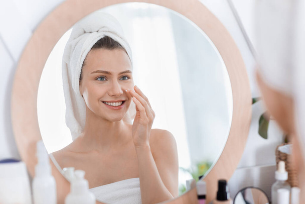 Happy young woman using face cream after shower - Photo, Image