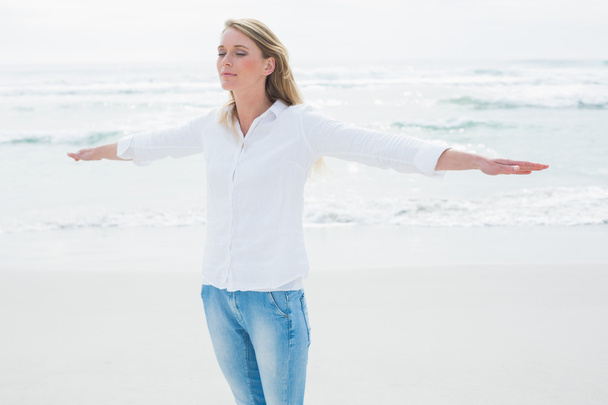 Woman with eyes closed and arms outstretched at beach - Foto, Imagen