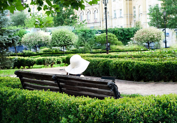Menina de chapéu branco com laptop no parque da cidade. Conceito de Distanciamento Social. Close-up
 - Foto, Imagem