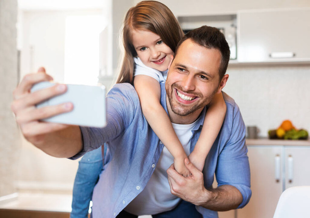 Vrolijke vader en dochter maken selfie plezier in de keuken - Foto, afbeelding