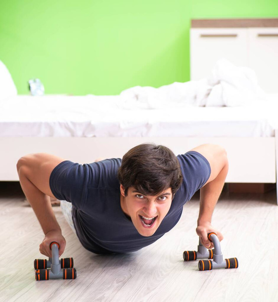 Young man in pajamas doing morning exercises - Foto, afbeelding