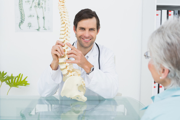 Male doctor explaining the spine to a senior patient - Foto, imagen
