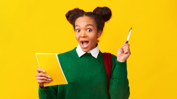 Afro adolescente in possesso di penna e notebook in studio - Foto, immagini