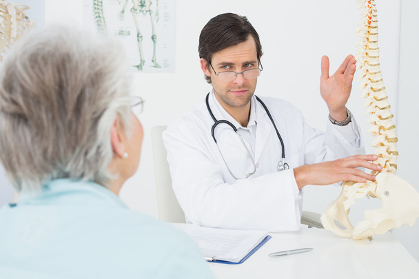 Male doctor explaining the spine to a senior patient - Fotó, kép