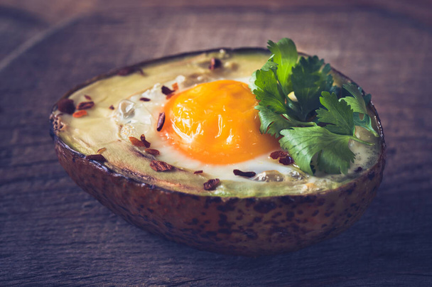Baked egg in avocado on the wooden board: top view - Photo, Image