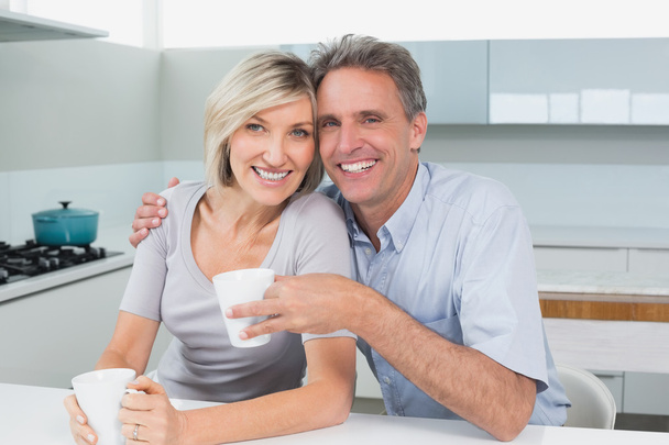 Happy loving couple with coffee cups in kitchen - Zdjęcie, obraz