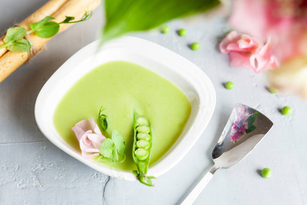 Homemade fresh green pea cream soup with pea sprouts and flowers - Photo, image