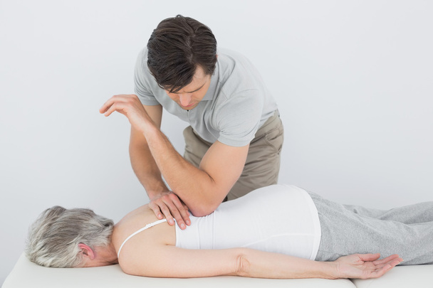 Male physiotherapist massaging a senior woman's back - Фото, зображення