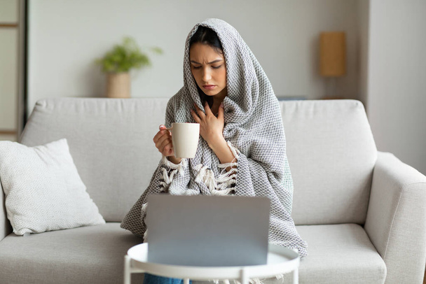 Enfermo chica bebiendo té sentado en el ordenador portátil de trabajo desde casa
 - Foto, imagen