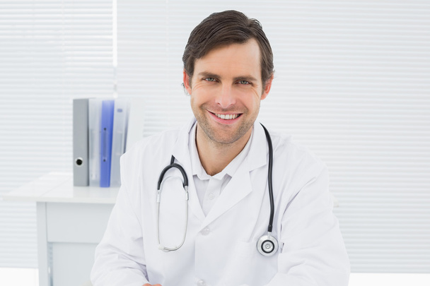 Smiling confident male doctor in medical office - Φωτογραφία, εικόνα