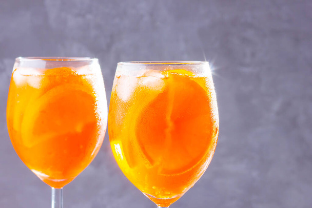 Aperol spritz cocktail on gray background. Two glasses of aperol spritz with orange slised. Summer cocktail in glass. Copy space - Photo, Image