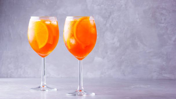 Aperol spritz cocktail on gray background. Two glasses of aperol spritz with orange slised. Summer cocktail in glass. Copy space - Photo, Image