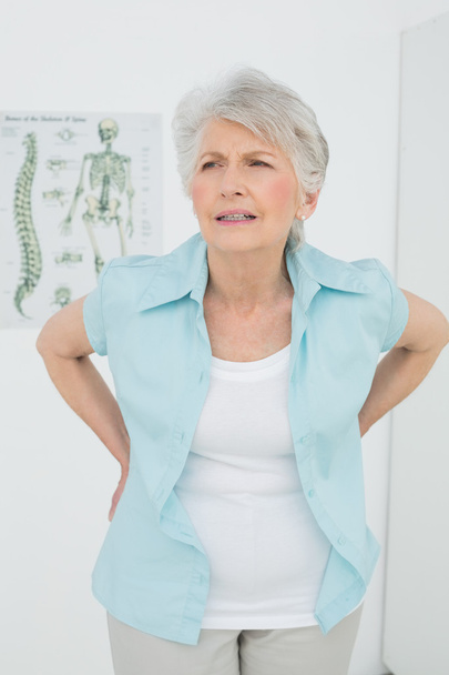 Senior woman with back pain in medical office - Foto, Imagen
