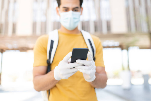 Spanyol fiatalember SMS-ezés okostelefonon keresztül a városban a COVID19 járvány kitörésekor - Fotó, kép
