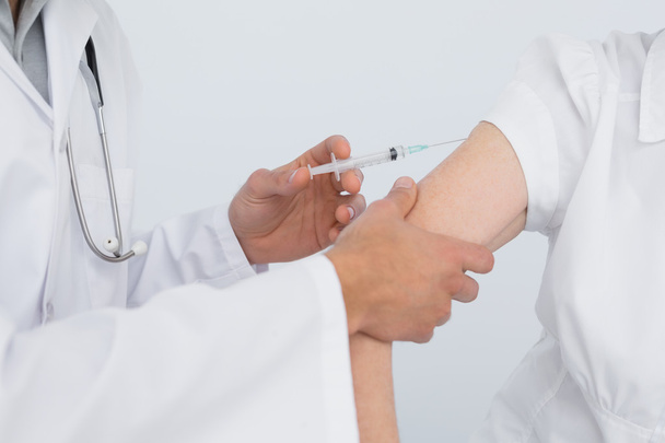 Close-up of hands injecting a female patient's arm - Fotó, kép