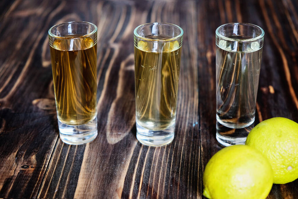 Meksikolainen kulta ja hopea tequila ja lime puupohjalla lähikuva - Valokuva, kuva