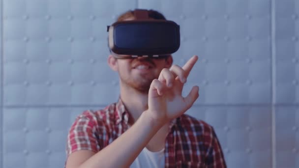 Nowoczesne technologie. Facet dotyka wirtualnej książki palcem używając nowoczesnych okularów VR w pomieszczeniu. Przystojny nastolatek w wirtualnej rzeczywistości, próbujący dostosować rzeczywistość. Prores 422 - Materiał filmowy, wideo