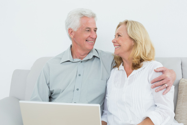 Senior couple with laptop on sofa in a house - Photo, Image