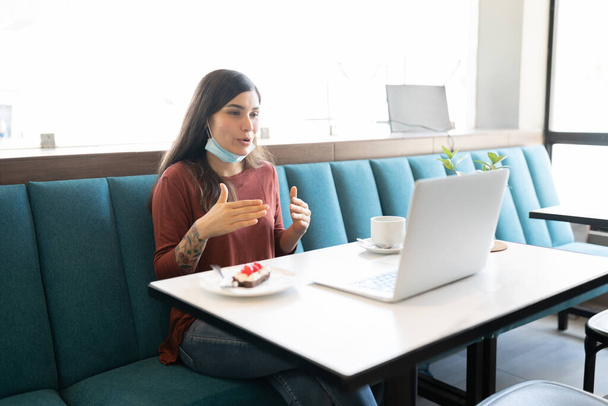 Латинська молода жінка жестикулює під час відеодзвінків через ноутбук у кафе. - Фото, зображення
