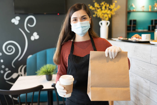 Fiatal nő barista kezében parcella és kávéscsésze étteremben - Fotó, kép
