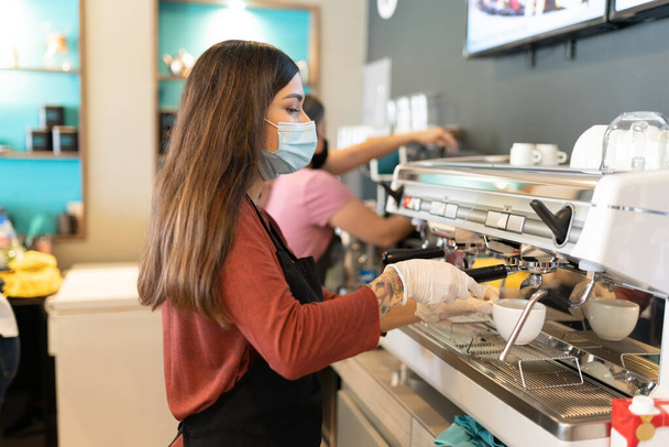Side view of young female barista making coffee in cafe - Photo, Image