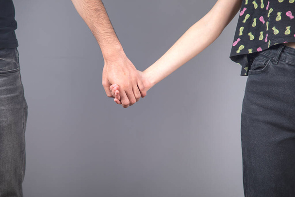 man and woman hand in hand on grey background - Φωτογραφία, εικόνα