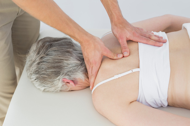 Male physiotherapist massaging a senior woman's back - Foto, immagini
