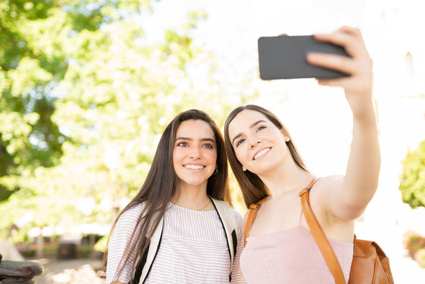 Mladá žena brát selfie s přítelem přes smartphone v parku - Fotografie, Obrázek