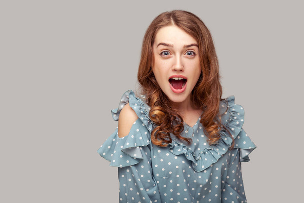 Wow, oh my god! Surprised excited brunette girl ruffle blouse looking at camera with amazement, open mouth in astonishment, shocked by unbelievable news. studio shot isolated on gray background - Photo, Image