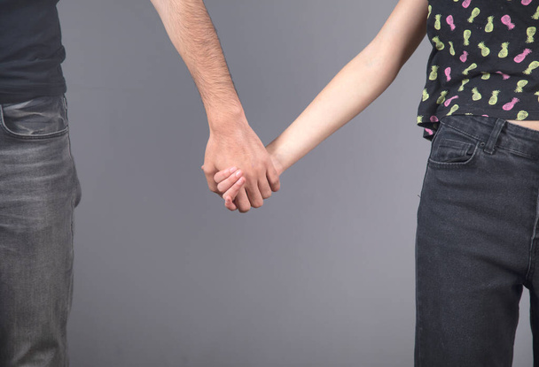 man and woman hand in hand on grey background - Foto, imagen