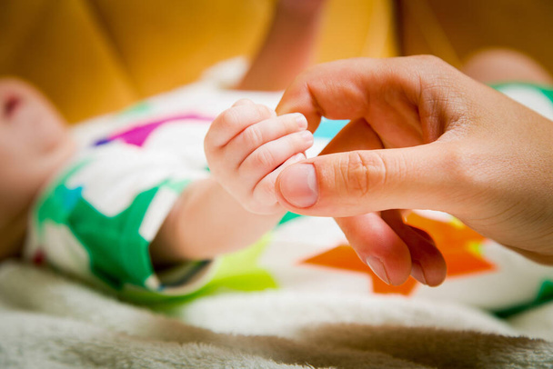 Kinderen. Baby 's. Kleine hand van een pasgeboren baby in de handen van gelukkige ouders - Foto, afbeelding