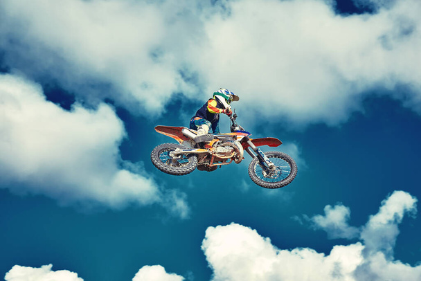 Ekstremalna koncepcja, wyzwij się. Ekstremalny skok na motocykl na tle błękitnego nieba z chmurami. Przestrzeń kopiowania, wszystko albo nic. - Zdjęcie, obraz