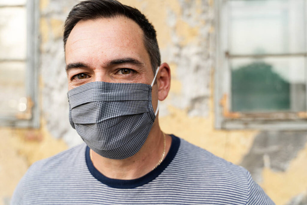 コロナウイルス発生による保護マスクを着用した成人白人男性の肖像-中年男性の社会的距離ウイルスの予防-屋外でのフロントビュー-新しい通常の概念 - 写真・画像
