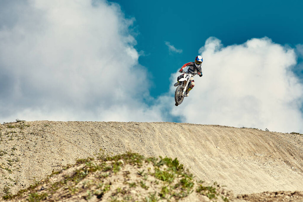 Extreme concept, challenge yourself. Extreme jump on a motorcycle on a background of blue sky with clouds. Copy space, all or nothing. - Fotó, kép