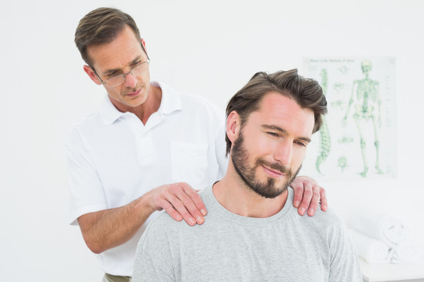 Male therapist massaging a content man's shoulders - Foto, afbeelding