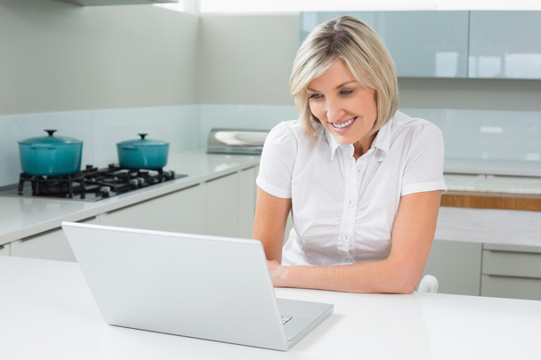 Casual woman using laptop in the kitchen - Zdjęcie, obraz