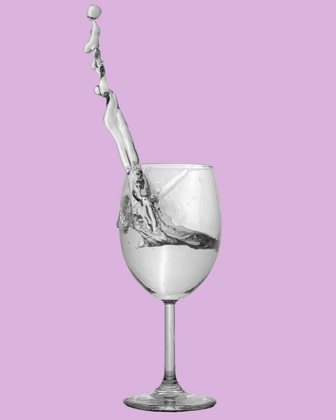 white wine spatter in a glass on a pink background - Фото, изображение
