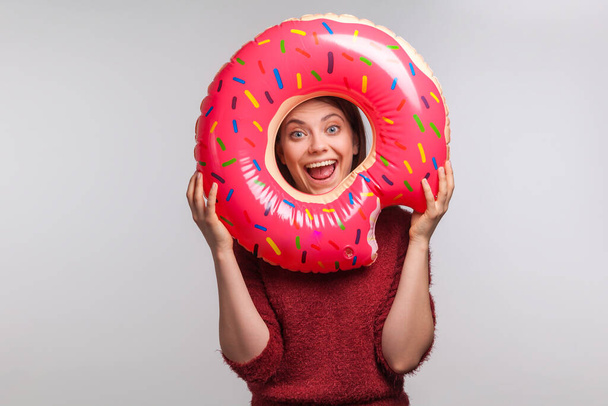 Optimistic funny girl looking through rubber ring with happy amazed expression, shouting for joy in anticipation of summer vacation, rest at seaside, travel concept. indoor studio shot isolated - Фото, изображение