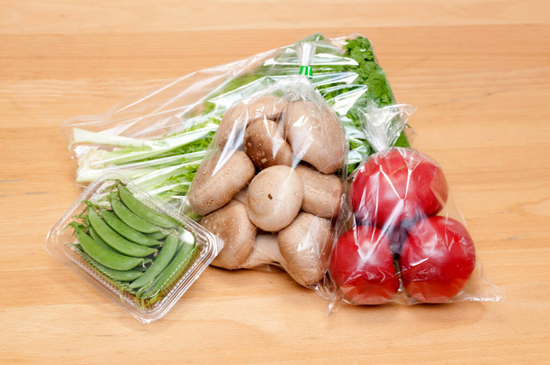 Свіжий гриб Шиітаке, помідори, гарбуз, васабі зелені овочі в поліетиленовому пакеті на дерев'яному тлі. Шопінг в магазині
.  - Фото, зображення